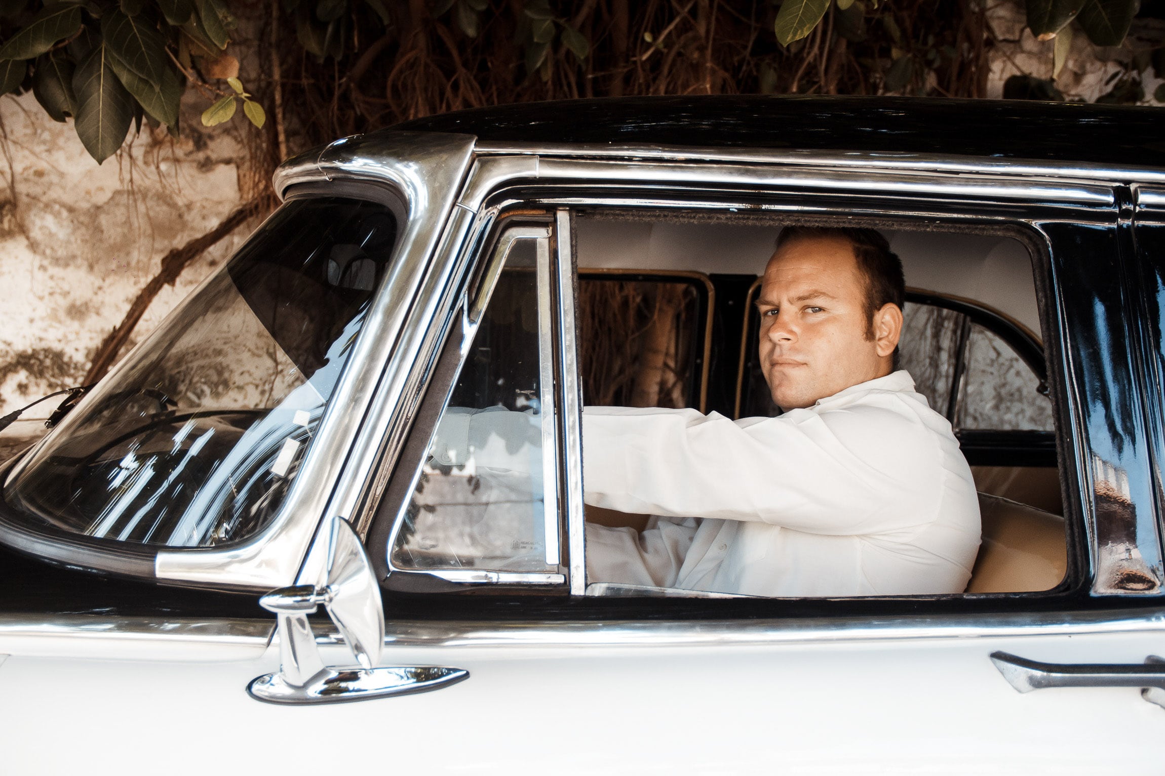 Chauffeur in blauen Oldtimer in Kuba