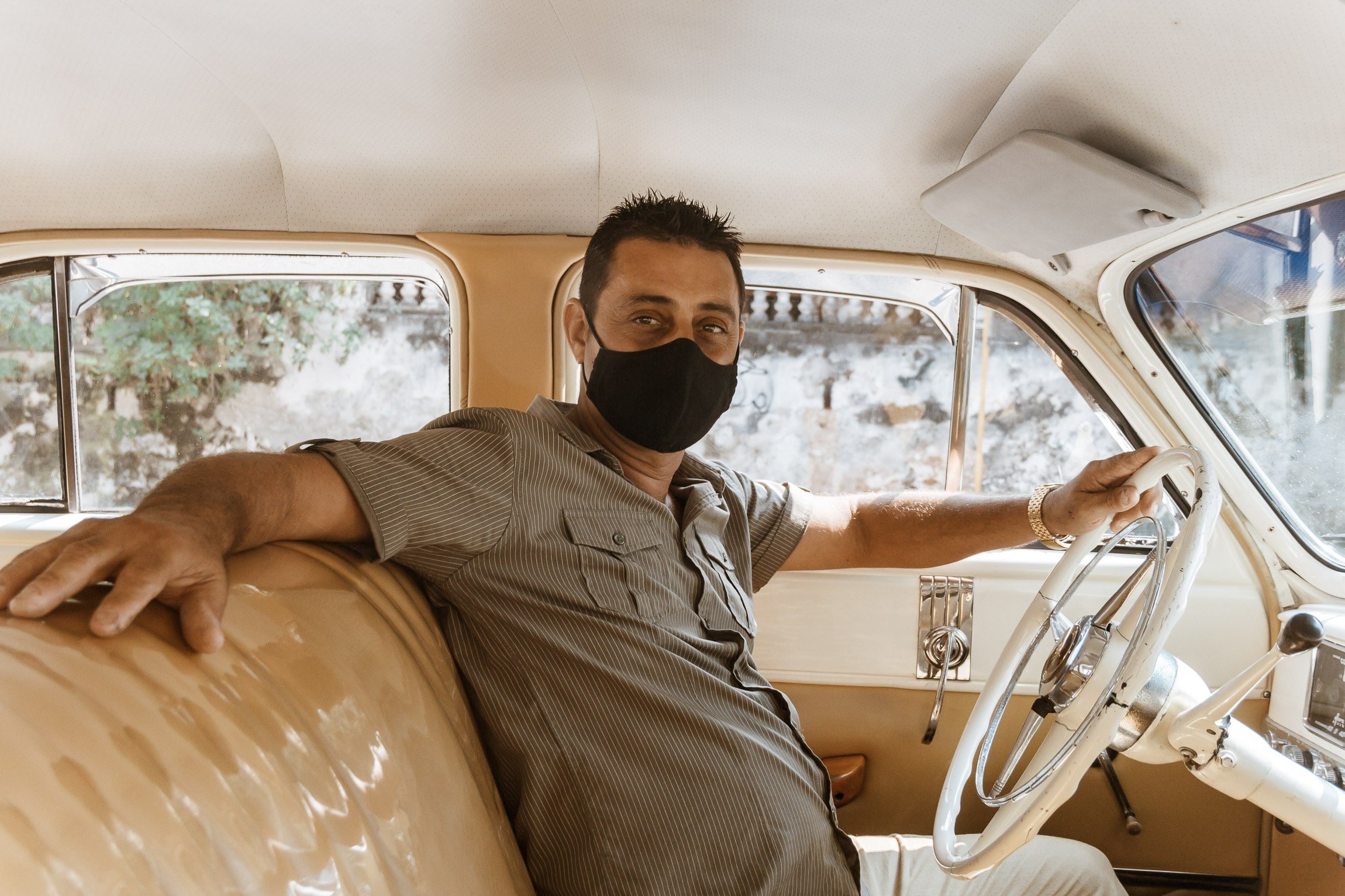 Chauffeur mit Maske im Oldtimer